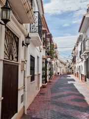 Nerja, Spain - October 9, 2021: Typical Andalusian street with whitewashed houses in a sunny day.  Nerja, beautiful touristic village in Costa del Sol. Malaga province, Andausia, Spain, Europe