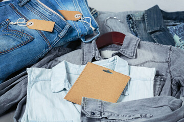 Sustainable still life with Stack of blue jeans and denim shirts on hanger and empty craft card....