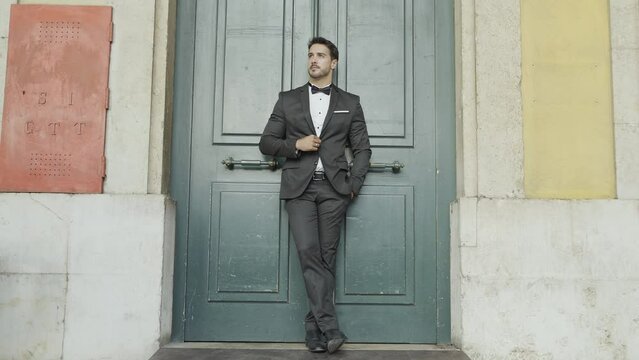 Gorgeous man in suit against the dark green door. Action. Groom or husband waiting for the bride.