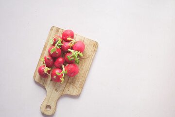 Fresh red radish bundle on chopping board on table 