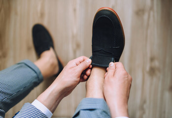 A young businessman in a plaid suit sits and puts his shoes on when going to work. Morning groom business. Wedding details.
