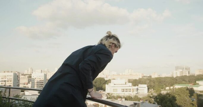 A man in a panic quickly climbs onto the roof canopy. Stock. A young man with white hair walking on the roofs of high-rise buildings.