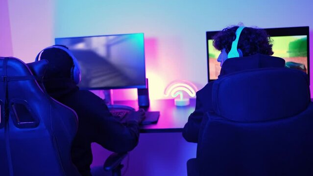 Two gamers from different backgrounds playing video games together and celebrating the victory of their team. Concept: Gaming, teamwork, multiculturalism