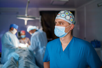 Fototapeta na wymiar Surgery specialist standing in operating room. Portrait of doctor in uniform and protective mask.