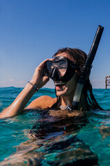 Joyful, carefree woman, snorkeling and swimming on beach vacation, having fun in the tropical water,  with a big toothy smile, laughing, enjoying her honeymoon