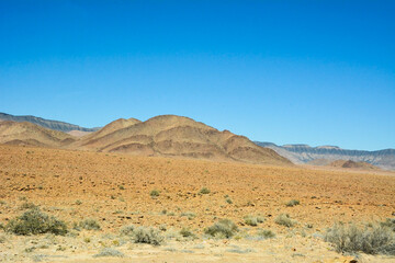 A rocky hill on a mountain slope near the desert against a clear blue sky. World climate change and global warming