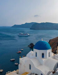 Fototapeta na wymiar Panoramic view of Church of Agios Nikolaos in Oia town in Santorini. Traditional and famous white houses and churches with blue domes in Aegean sea