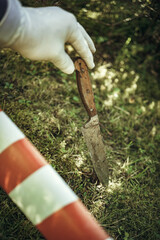 The murder weapon at the crime scene. The work of a criminologist in white gloves. Cold steel.