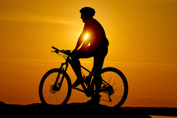 Obraz premium Silhouette of cyclist travelling. Outdoor sunset bicycle rider.
