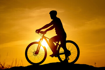 Fototapeta na wymiar Sunset shadow of cyclist. Silhouette biking summer ride.