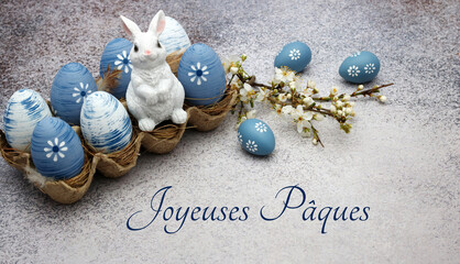 Carte de Pâques : Oeufs de Pâques bleus avec des fleurs et des lapins de Pâques avec le texte...