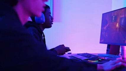 Two young friends playing video games as a team and celebrating joint triumphs and having fun in their gaming room. Concept: video game, streaming, online