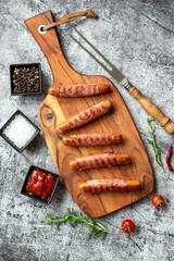 sausages wrapped in bacon, grilled on a stone background