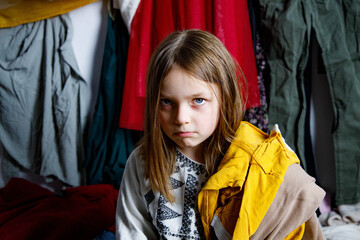 Dziewczynka zero waste - eko - era konsumpcjonizmu - za dużo ubrań, niezadowolone dziecko - smutne dziecko - nie wie, w co się ubrać