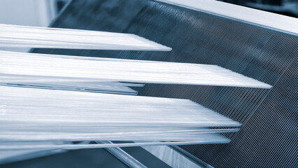 Obraz premium synthetic textile thread, thread at industrial weaving manufacturing machine, textile fabric production industrial concept background