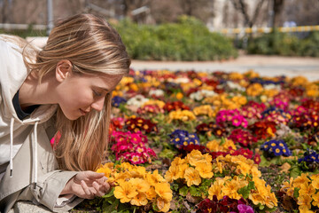 Fototapeta premium Enjoying spring's first blooms, a young Caucasian woman gently touches a flower.