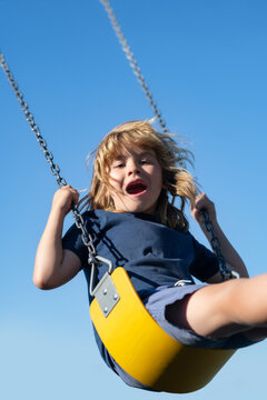 Child boy on swing. Little kid swinging on playground. Happy cute excited child on swing. Cute child swinging on a swing. Crazy playful child swinging very high on sky.