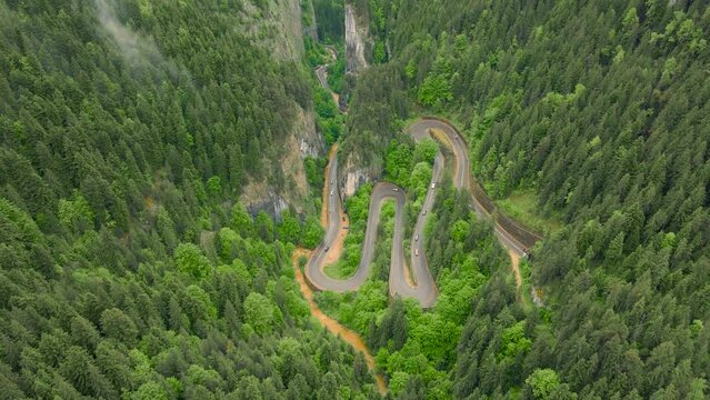 Aerial view of a winding road in the mountains, shot from a drone from a higher altitude and a low camera angle for a top view. Video of a serpentine road in the mountains in Bicaz area, Romania.