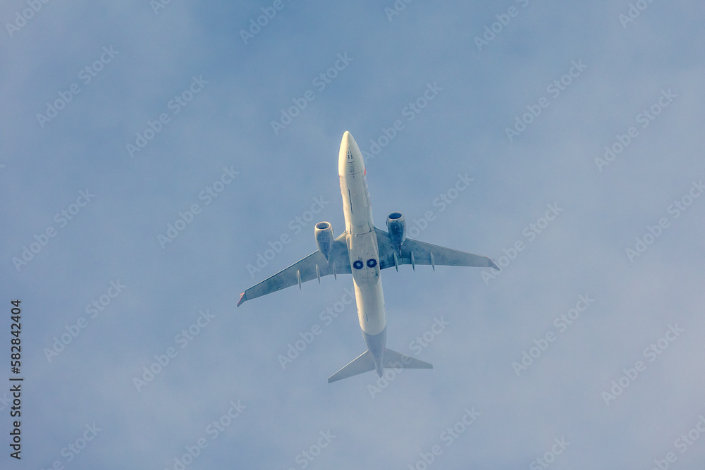 Wall mural a jet plane flying in a blue sky between clouds. transportation. air travel.