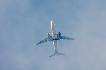 A jet plane flying in a blue sky between clouds. Transportation. Air travel.