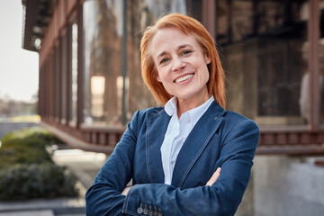 Fototapeta premium Determined middle-aged businesswoman smiling, building her success story.
