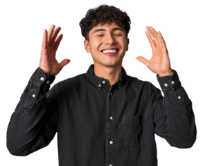 Young latin man praying for luck, amazed and opening mouth looking to front.