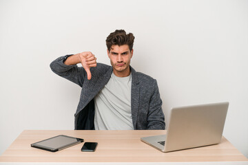Young entrepreneur man working with a laptop isolated showing thumb down, disappointment concept.