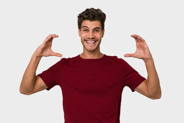 Young handsome caucasian man isolated on white background holding something with palms, offering to camera.