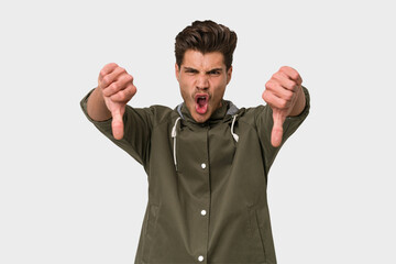 Young handsome caucasian man isolated on white background showing thumb down and expressing dislike.