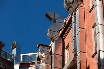 Large shiny ventilation pipes on the brick wall on the outside of the building.