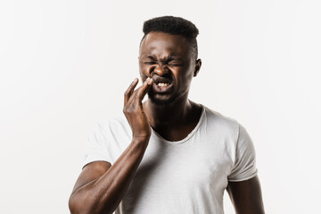 Toothache of african man on white background. African american is touching cheek and feeling teeth...