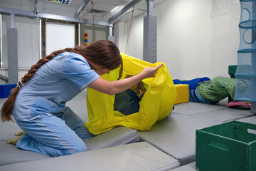 Child girl in roller tonnel during sensory integration session. child with physiotherapist in...