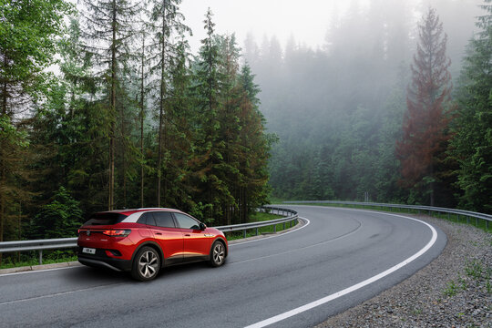 Carpathian mountains, Ukraine - June 24, 2021: Red car on highway, new Volkswagen ID.4 on road in forest