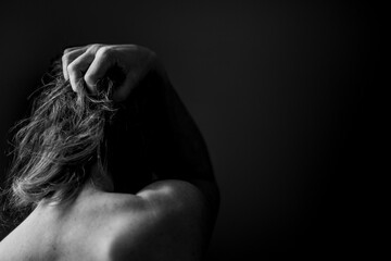 Black and white picture of the back of a caucasian woman in grief or anger or despair