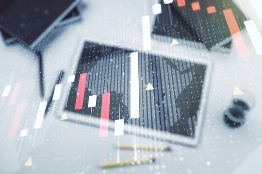 Abstract creative financial graph with world map and modern digital tablet on desktop on background, top view, financial and trading concept. Multiexposure