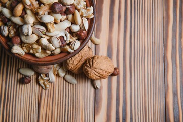 mixed nuts in a bowl on wooden table, top view with copy space.