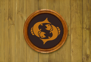 Fototapeta premium The sign of the zodiac Pisces in a round frame on the wall of the boards