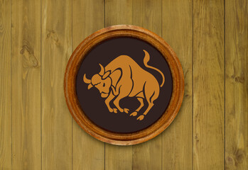 The sign of the zodiac Taurus in a round frame on the wall of the boards