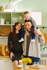 a happy family. pregnant mom, son and dad In the kitchen. a cozy house 