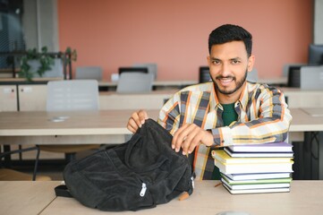 Handsome young Indian boy student with books and backpack at university. Education concept