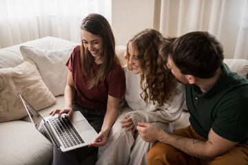 Portrait of a happy family of three using laptop at home.