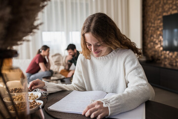 Young girl working on her home work, while her parents are having a serious conversation in the background.