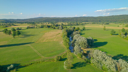 AERIAL: Scenic countryside with slow-flowing river winding across green fields