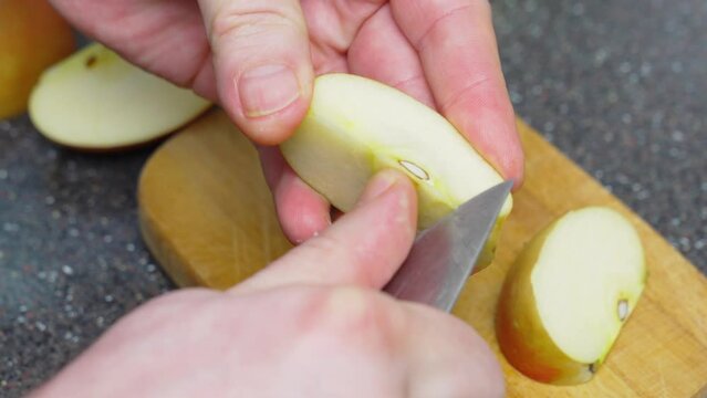 men's hands are cut into pieces and apples are peeled on a wooden cutting board.