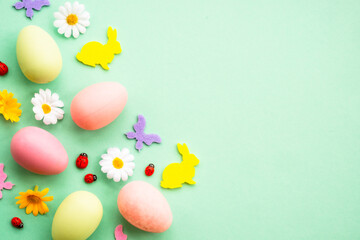Easter background. Eggs, rabbit, spring flowers and butterfly. Flat lay mock up at green background.
