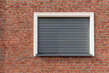 a brick wall with window and closed shutters