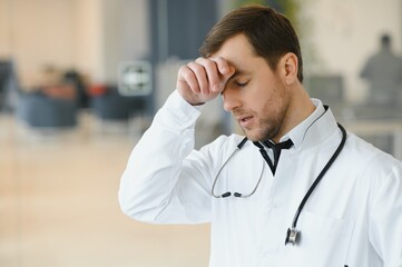 Stressed male doctor. Mid adult male doctor working long hours. Overworked doctor in his office....