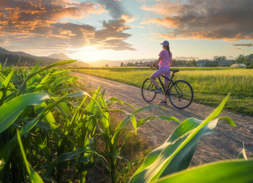 Woman on mountain bike on gravel road at sunset in summer
