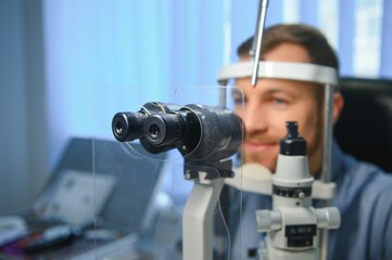Adult man eyesight test with binocular slit-lamp. Checking retina of a male eye close-up....