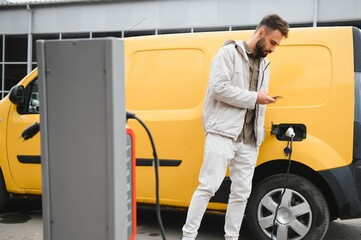 Man charging electric car by the work